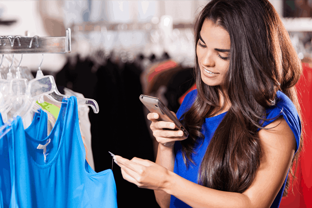 a woman takes a snapshot of a price tag with her mobile phone in a boutique